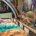Children leaning on a glass counter looking at all the different flavours of ice cream.