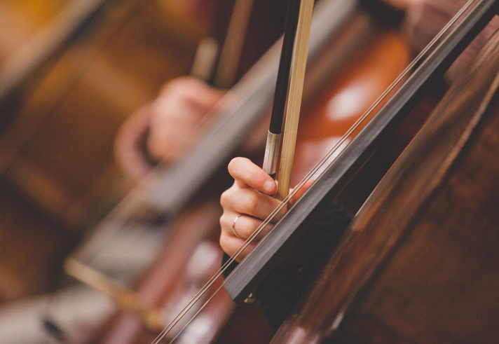 A close up of cellos being played.