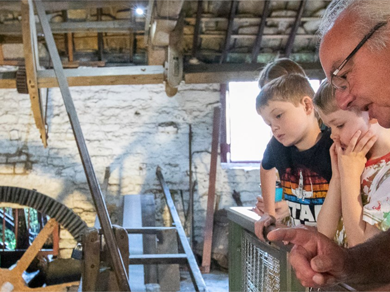 A man telling three children about the history of the Shepherd Wheel Workshop.