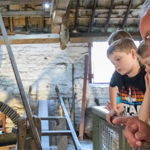 A man telling three children about the history of the Shepherd Wheel Workshop.