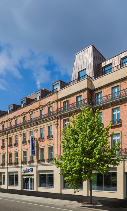 Exterior of the Radisson Blu hotel with trees in front.