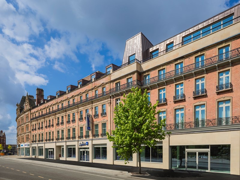 Exterior of the Radisson Blu hotel with trees in front.