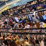 People browsing through huge rails of vintage clothes.