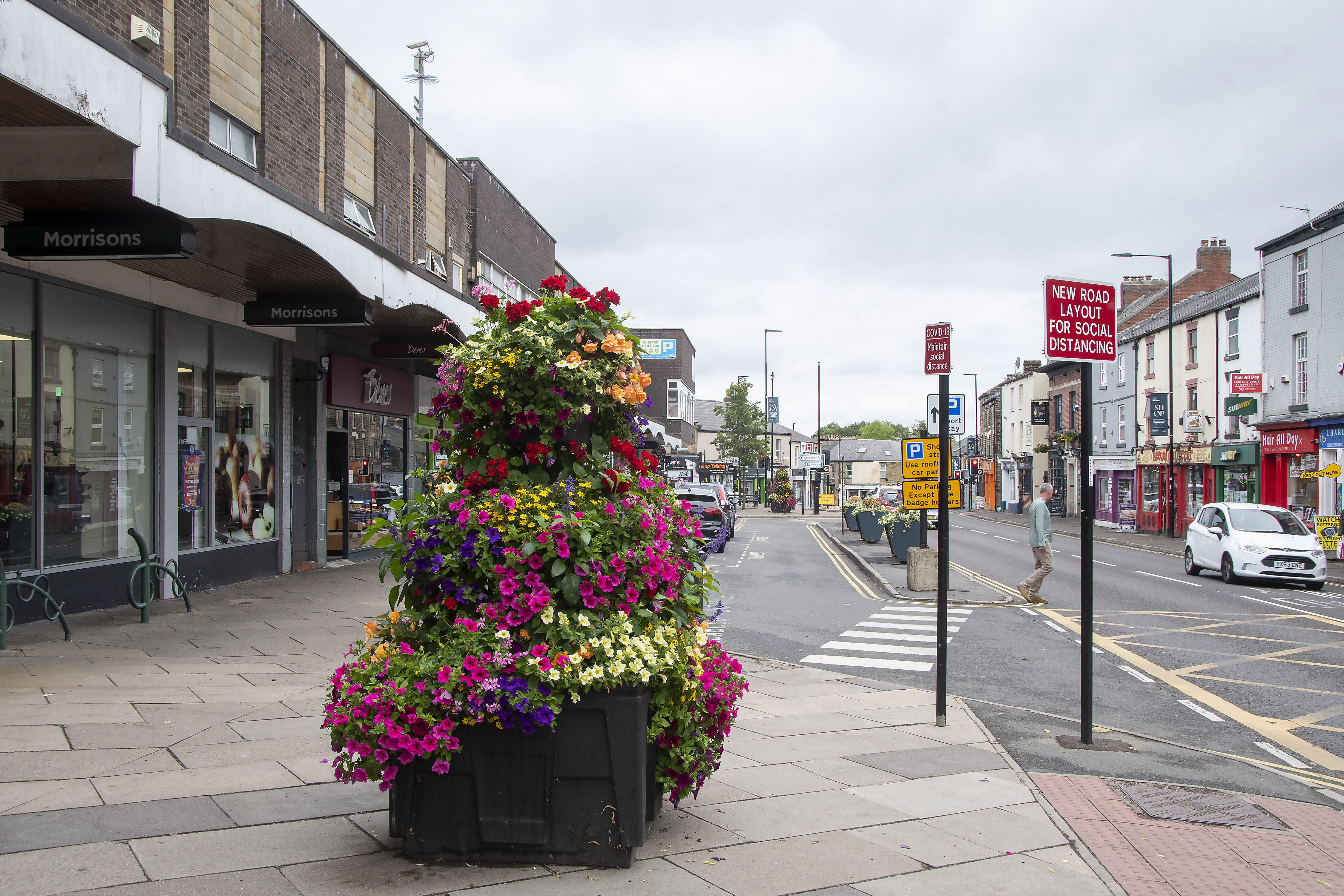 A large display of flowers in a huge planter on the pavement.