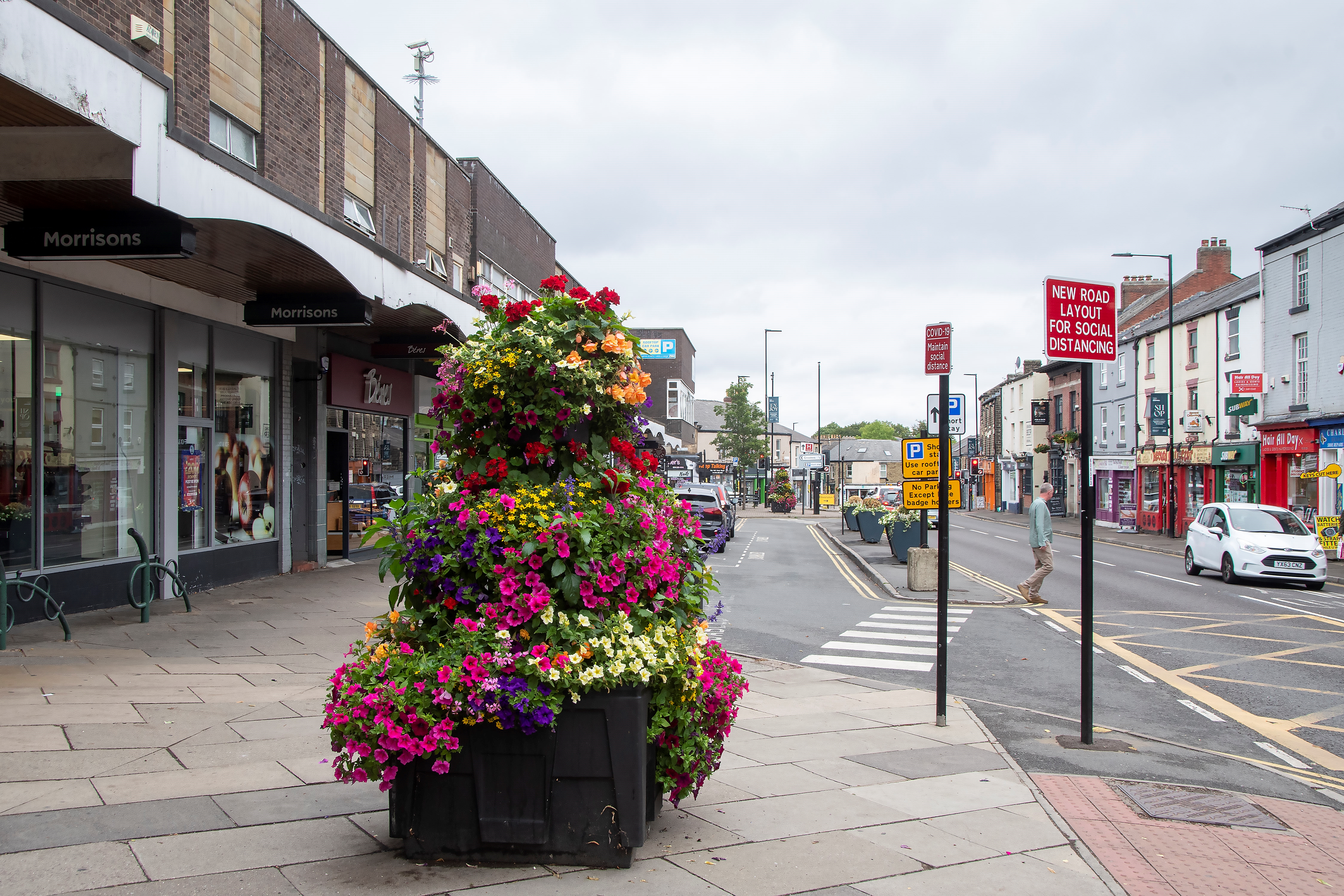 A large display of flowers in a huge planter on the pavement.