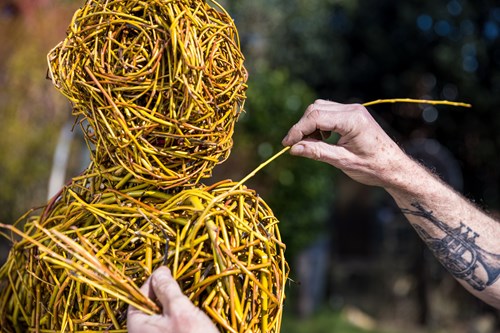 A man weaves a figure out of willow.