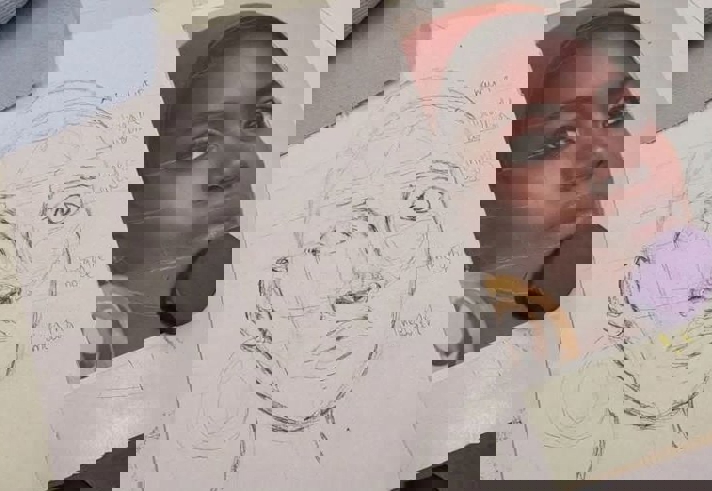 A pencil drawing of a face and a photo that is the source material for the drawing.