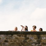 Four people looking over a high wall, one with a telescope, playing Treasure Hunt Sheffield.