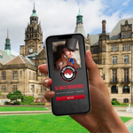 A smartphone being held up in front of Sheffield Town Hall and the Peace gardens, with a tour App on the screen.
