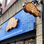 A side view of the sign outside of the shop, which reads La Croissanteria, the title is placed on top of croissant 