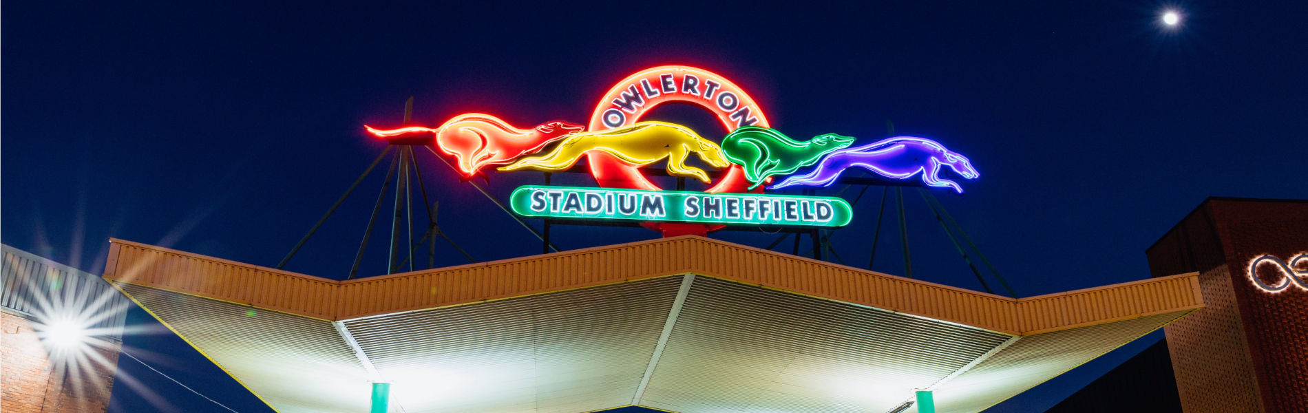 The neon sign above the entrance to Owlerton Stadium, depicting running greyhounds.