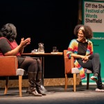 Close up of two people having a conversation on stage with an Off the Shelf banner in the background. 