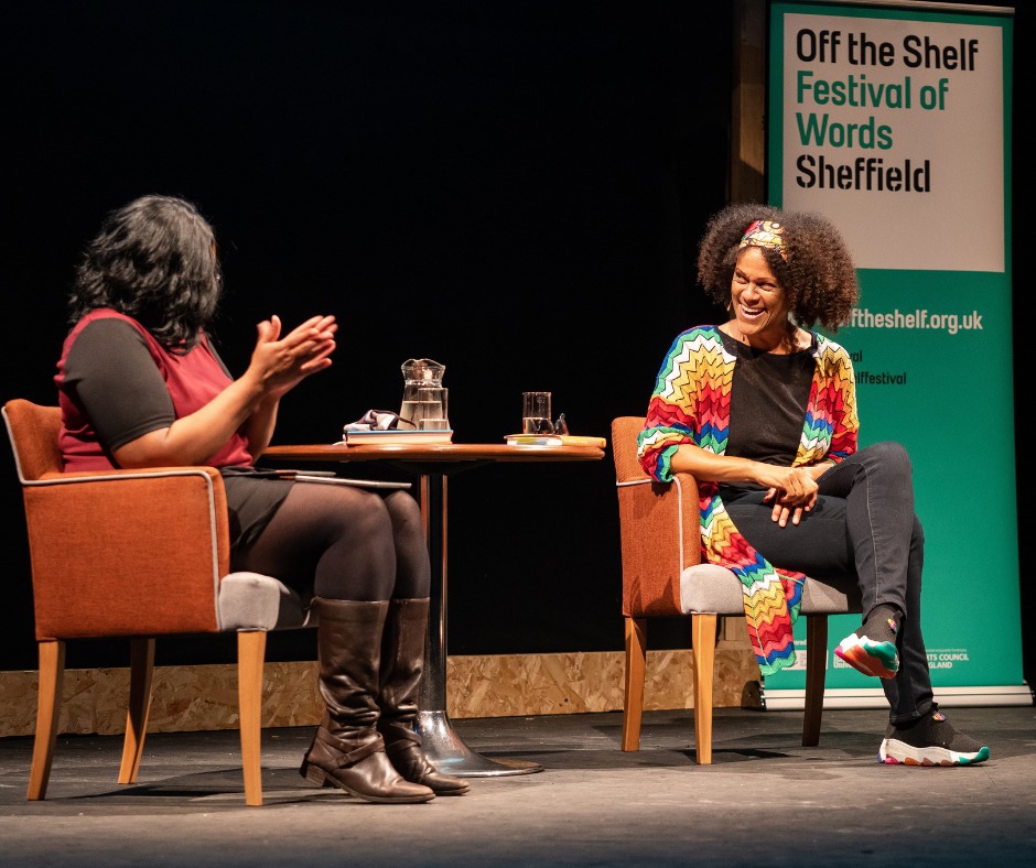 Close up of two people having a conversation on stage with an Off the Shelf banner in the background. 