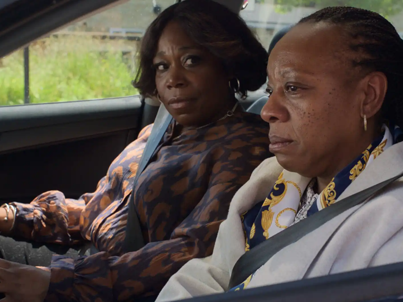 Two women of African heritage sitting in a car.