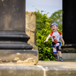 A child running in between some large stone pillars.  