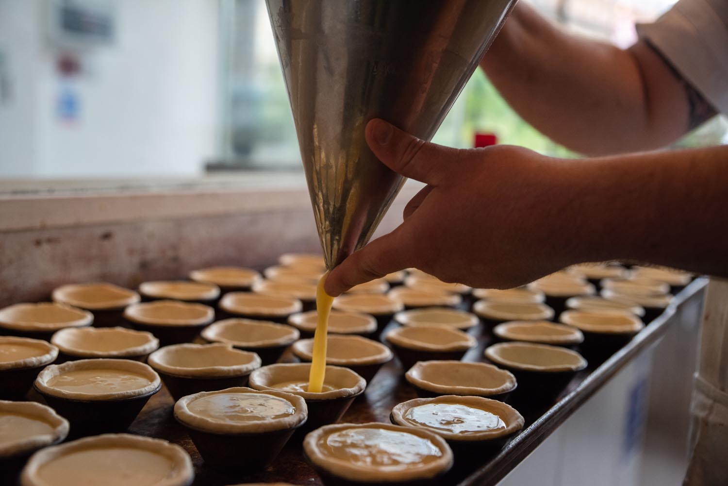 A person is filling small pie crust with filling.