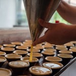 A person is filling small pie crust with filling.