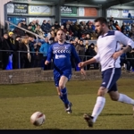 Men playing football in front of a crowd.