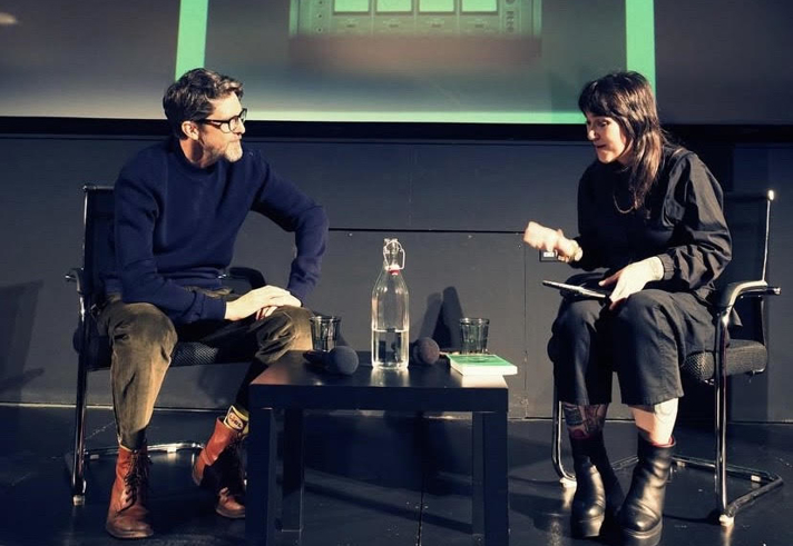 Two people, on a stage, having a discussion.