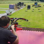 A person firing a crossbow at a target on a shooting range.