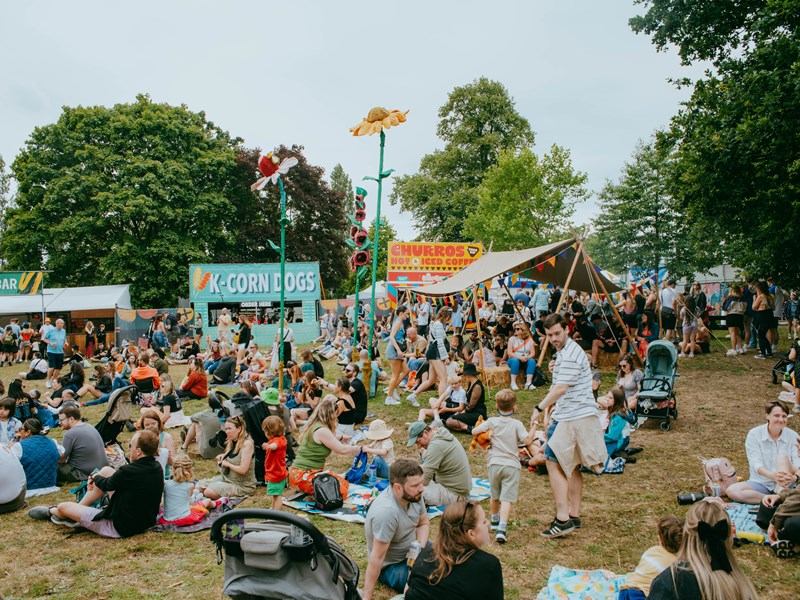 Families sit out on picnic blankets eating as other people queue for food from street food stalls at Tramlines festival