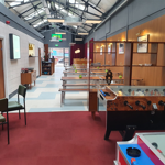 A photo looking down the length of Neepsend Social Club & Canteen with tables and chairs and Fussball tables