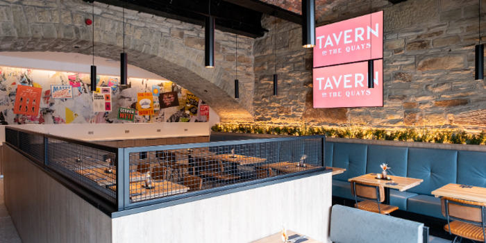 The interior of Tavern on The Quays, with bare stone walls and rows of tables and chairs.