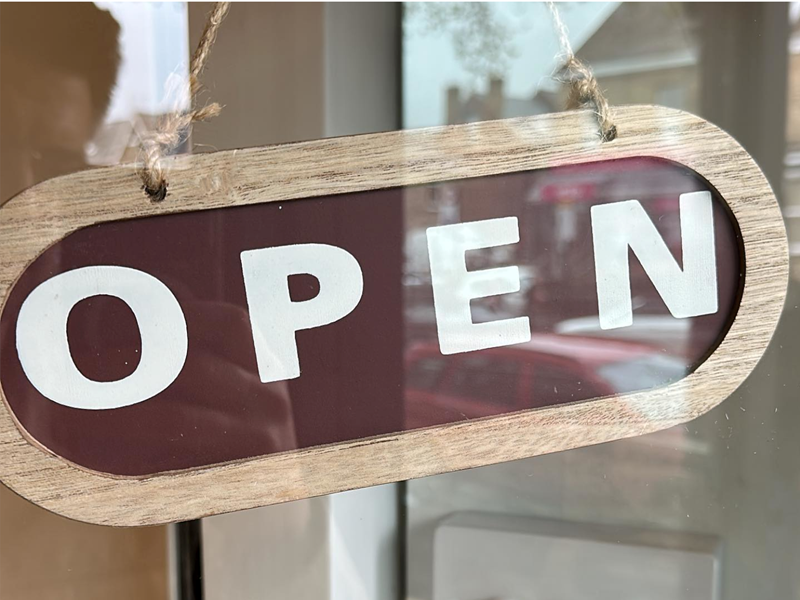 A wooden Open sign hanging in the door at Gills & Co.