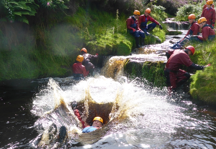 People training in a river, all of whom are wearing safety gear.