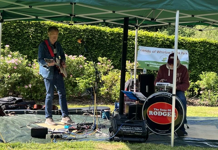 A band playing live in a park under a gazebo.