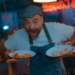 A chef holding two plates of food that are ready to go.