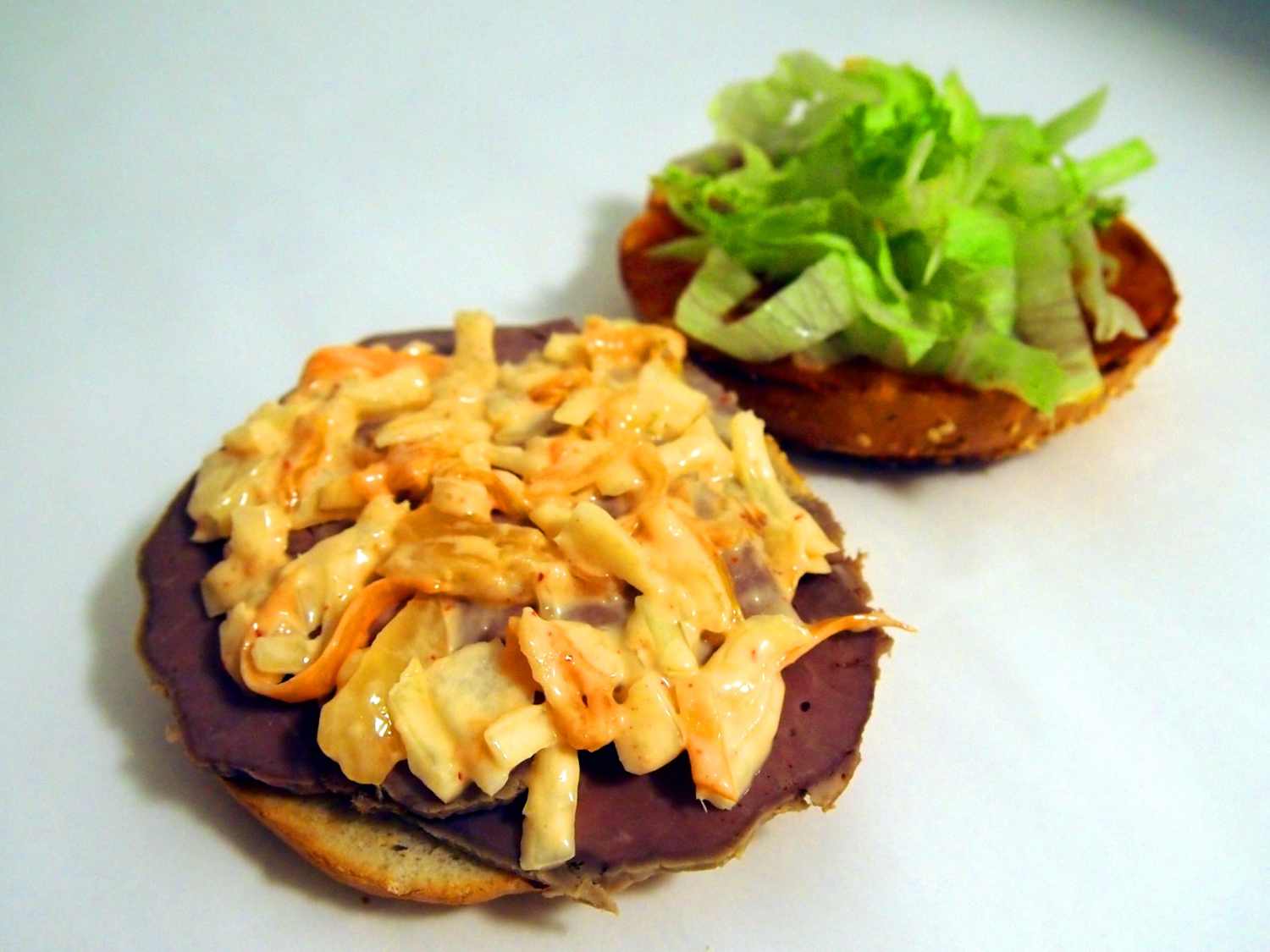 A bagel being prepared with fillings.