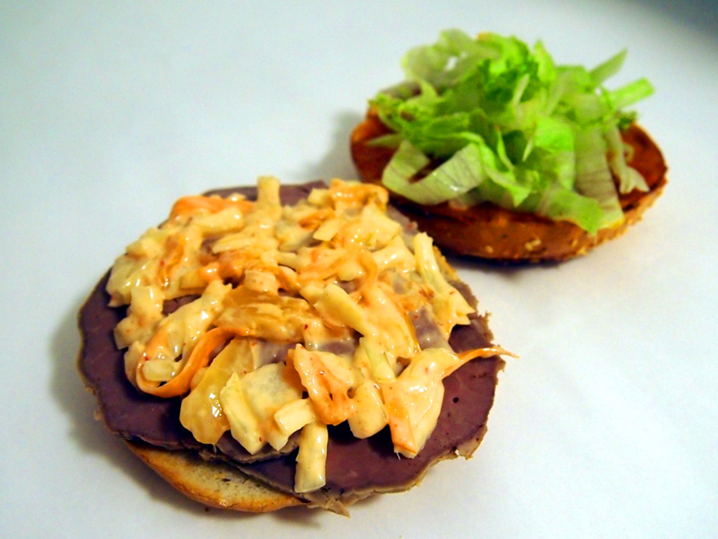 A bagel being prepared with fillings.