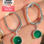 A close-up of a hand holding a pair of earrings.