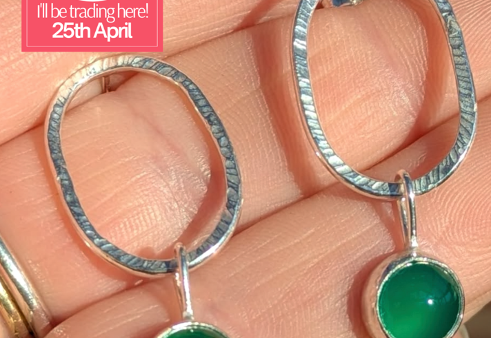 A close-up of a hand holding a pair of earrings.