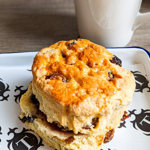 A scone on a plate with a mug of tea.