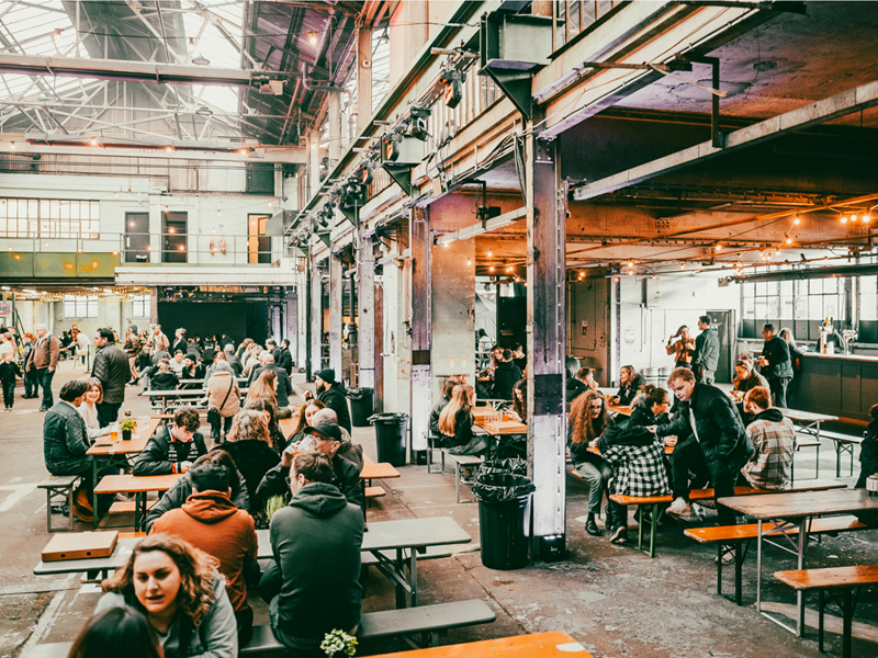 Rows of tables with benches, with people dining, at The Steamworks.