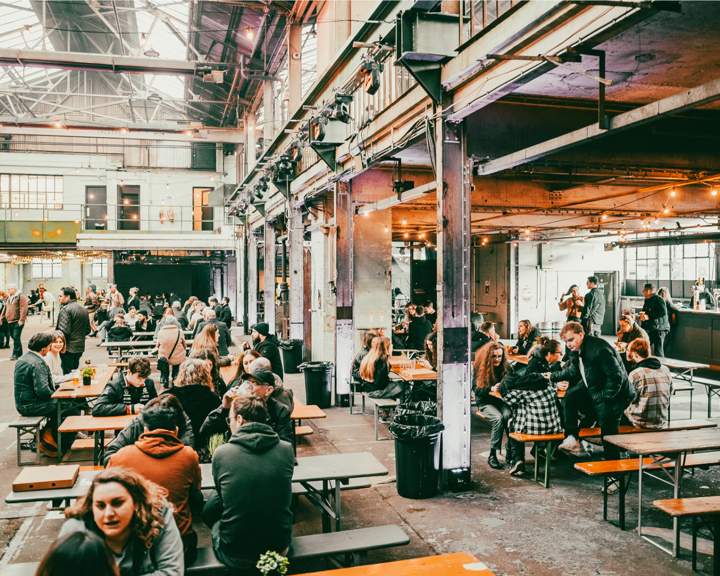 Rows of tables with benches, with people dining, at The Steamworks.