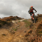 A person mountain biking up a steep hill in the countryside.