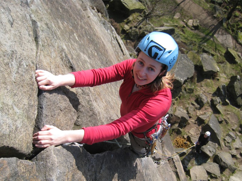 A woman climbing a rock face. She is smiling.