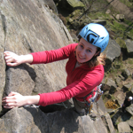 A woman climbing a rock face. She is smiling.