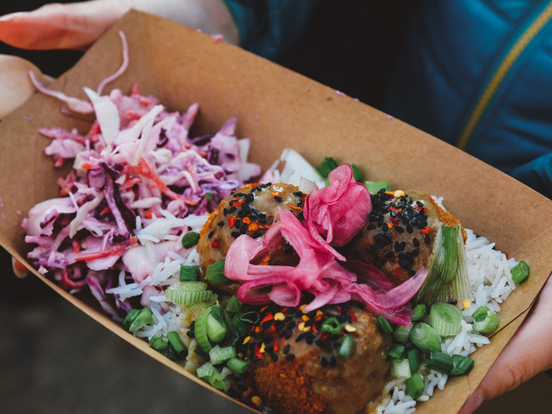 Someone holding at takeaway tray full of food.
