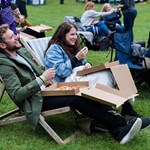 People sat in deck chairs, enjoying a pizza and watching a film at an outdoor cinema.