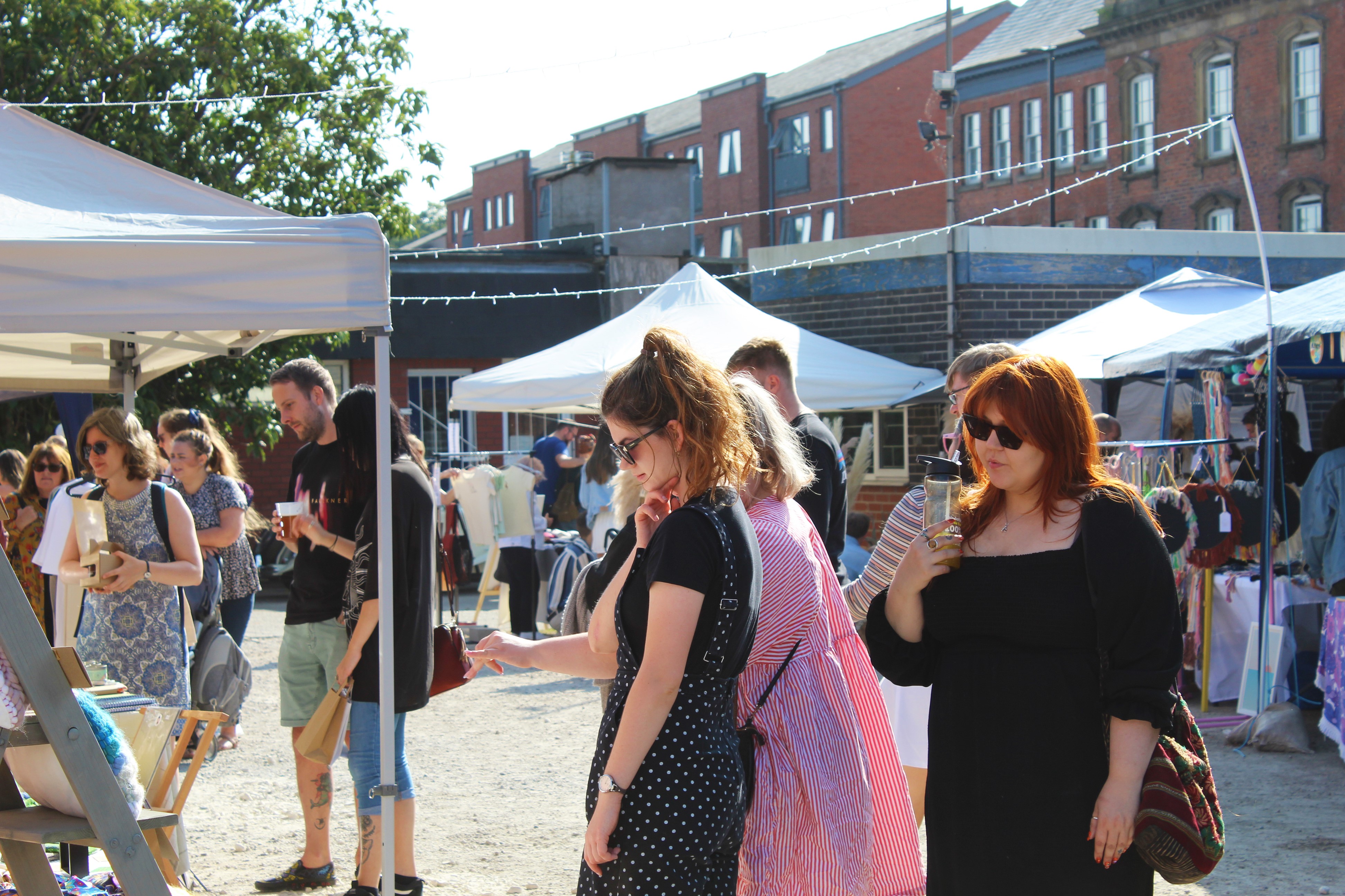 People looking through the stalls at Rex Market on a sunny day.