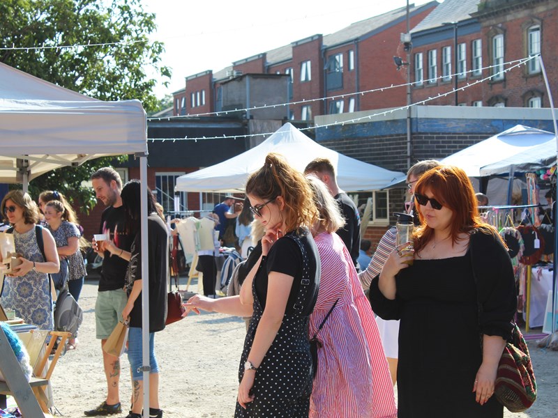 People looking through the stalls at Rex Market on a sunny day.