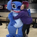 A person hugging a person in an alien costume.