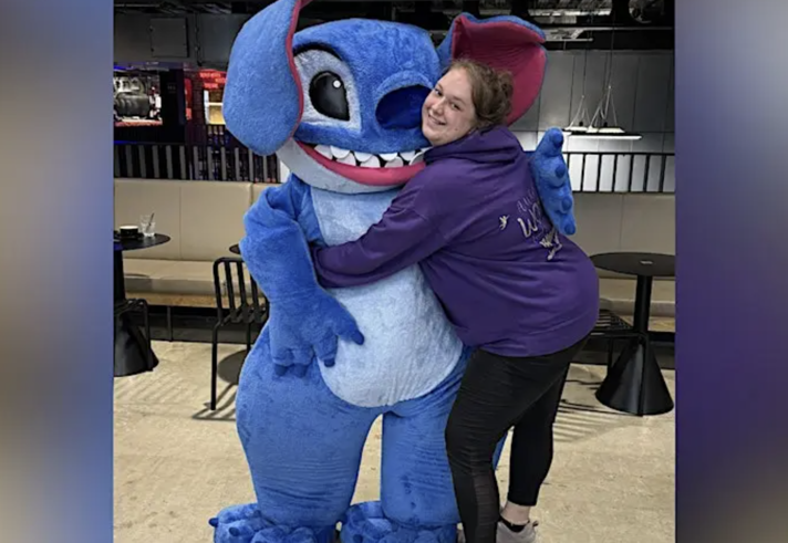 A person hugging a person in an alien costume.