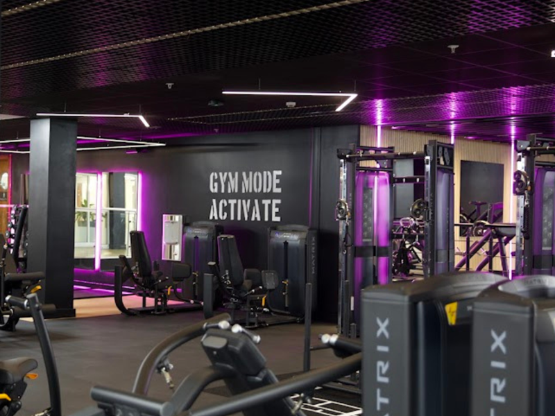 Gym equipment illuminated by purple lighting.