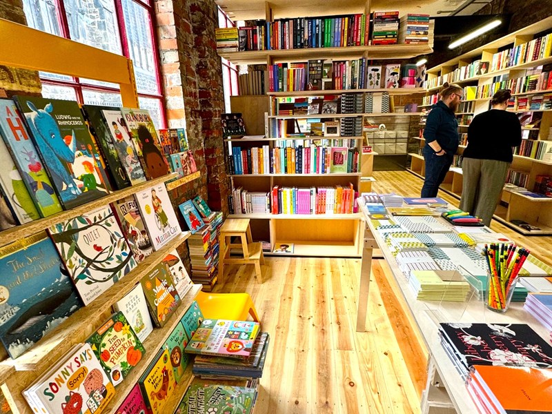The interior of La Biblioteka bookshop, with all the walls lined with wooden shelves filled with books for sale.