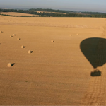 A hot air balloon flies over a scenic landscape.